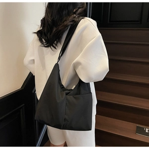 Detail of adjustable wide shoulder strap on black nylon hobo bag shown on model