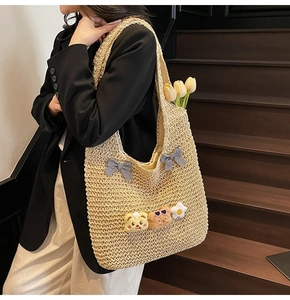 Détail du sac cabas en paille tissée avec nœuds à carreaux et breloques en peluche