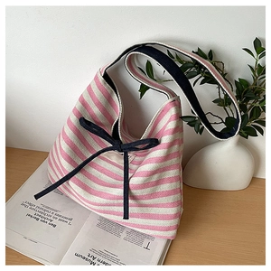 Detailed view of pink striped canvas tote bag with a blue bow on a wooden desk