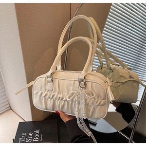 Detail of cream pleated bowling bag with pearl lace bow charm and metal zipper closure