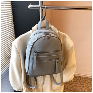 Detail of light blue lychee pattern leather backpack with silver zippers and pockets