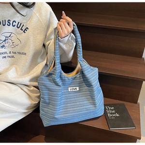 Detail van blauw gestreepte canvas tas met LOVE-patch en mosterdgele binnenvoering