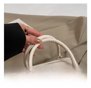 Detail view of the thick round leather handle with silver metal D-ring and stitching