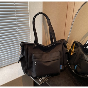 Macro detail of black nylon tote bag with side yellow drawstring and front zip pocket
