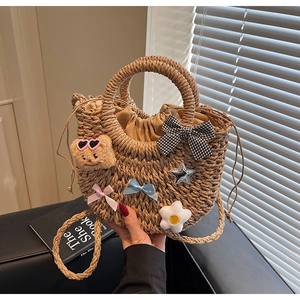 Détail du sac panier en paille avec pendentif ours en peluche et nœuds décoratifs