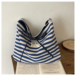 Close-up of blue and white striped canvas tote featuring a black bow and SEE YOU label