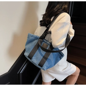 Détail du grand sac cabas en jean bleu avec large bandoulière noire et patch logo D