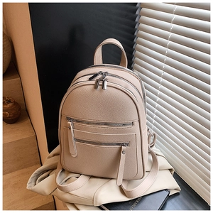 Detail of beige pebbled leather backpack with multiple zippers and gunmetal hardware