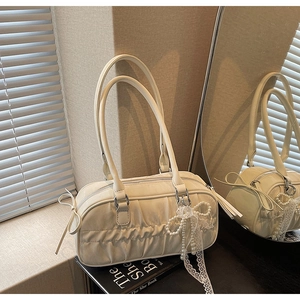 Detail of white pleated handbag with bow accents and pearl lace charm pendant