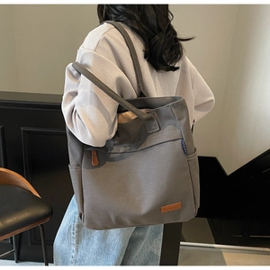 Detail view of large canvas tote bag showing texture and leather brand patch on model