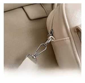 Detail showing high-quality silver metal hook and D-ring on cream PU leather crossbody bag