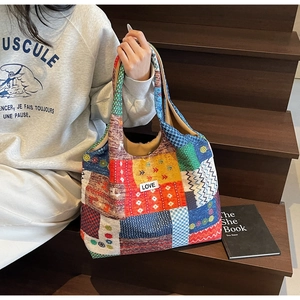 Detail van kleurrijke patchwork canvas tas met witte LOVE-patch op een houten trap