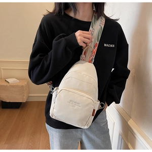 Detail of off-white crossbody bag with embossed logo and colorful geometric strap design