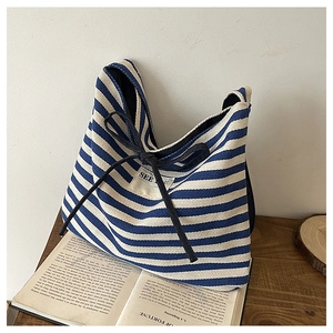Detailed shot of blue striped canvas tote featuring See You tag and black ribbon bows