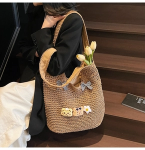 Détail du sac cabas en paille tressée avec nœud à carreaux et breloques ours en peluche