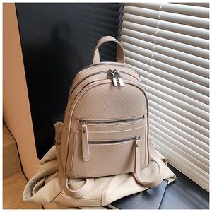 Close-up of beige pebble leather backpack featuring silver zippers and dual shoulder straps