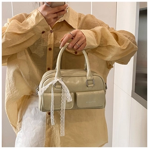 Detail showing the cream faux leather texture and white lace bow on the vintage style bag