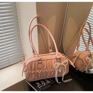Detail of pink pleated bowling bag with pearl lace bow charm and soft leather texture