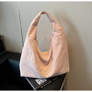 Dettaglio della borsa tote imbottita in nylon rosa chiaro su un divano in pelle