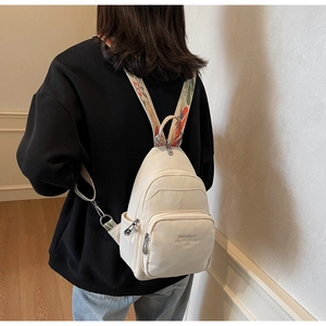 Detail of cream white backpack with jacquard strap and embossed front pocket on a model