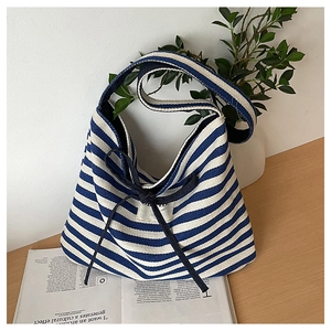 Detail of blue and white striped tote bag with a decorative black bow and shoulder strap