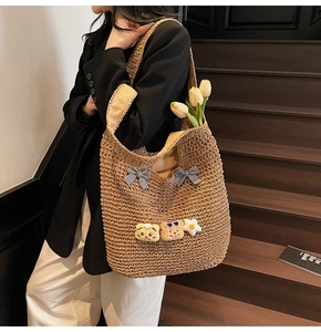 Gros plan d'un sac cabas tressé marron avec des nœuds vichy et d'adorables oursons en peluche