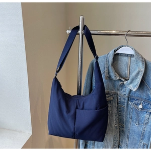 Detailed view of dark blue nylon hobo bag featuring adjustable strap and front pocket
