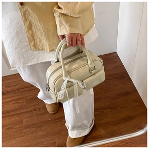 Detail shot of a mint green patent leather boston bag with elegant white lace ribbons