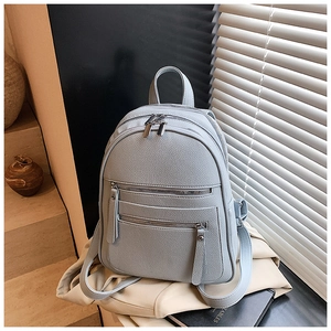 Close-up of a light blue-grey pebble leather backpack with multiple zip compartments
