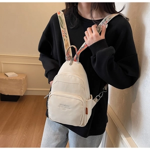 Detail of off-white small backpack with colorful floral embroidered strap and zipper
