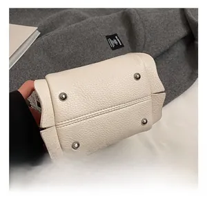 Close-up of white lychee leather bucket bag base featuring four silver protective metal studs