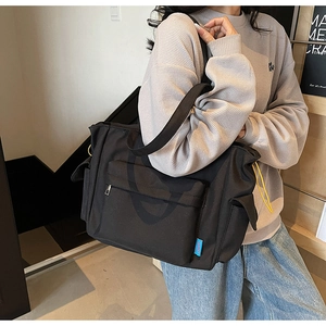 Detail of vintage black canvas bag showing front zipper pocket and side flap compartments