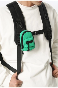 Close-up of bright green mini backpack pouch with black clip on chest strap