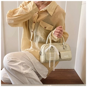Detail of light green faux leather handbag with lace bow and front pockets on model