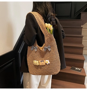 Détail du sac à bandoulière en paille avec nœuds à carreaux et patchs d'ours en peluche