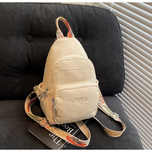 Detailed view of beige crossbody bag with colorful ethnic strap and triple zip pockets