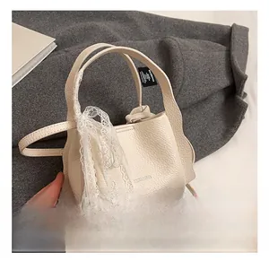 Detail of cream white bucket bag with litchi texture leather and elegant lace ribbon decoration