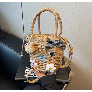 Détail du sac seau en paille fait main avec rubans, breloques et décor d'ours peluche