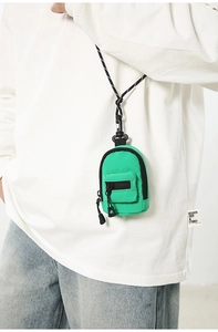 Mini green backpack-style neck pouch with woven cord, shown on model for lifestyle view