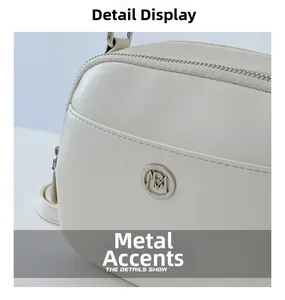Detail van een crèmewitte crossbodytas van imitatieleer met een zilveren metalen logo