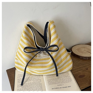 Close-up of yellow striped canvas tote bag with black bow and See You label