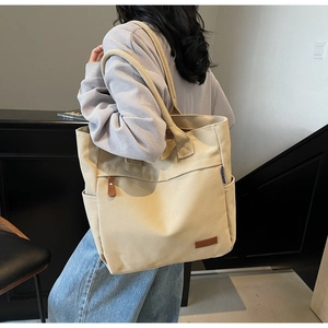 Detail of beige canvas tote bag showing dual straps and side pocket for daily commute