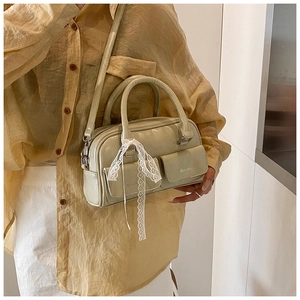 Detail of light green leather handbag featuring white lace bow and dual front pockets
