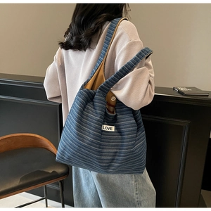 Detail van de blauw-wit gestreepte canvas tas met LOVE-patch en mosterdgele voering