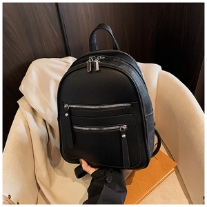 Detail of black pebbled leather backpack showing silver metal zippers and multi-compartment design