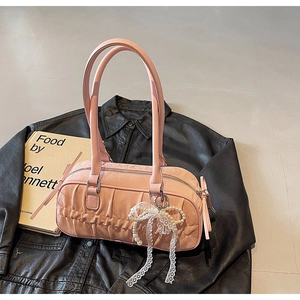 Pink pleated leather bowling bag with pearl lace bow detail on a black jacket