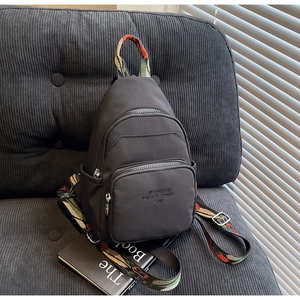 Close-up of black nylon chest bag with bohemian strap on a velvet background