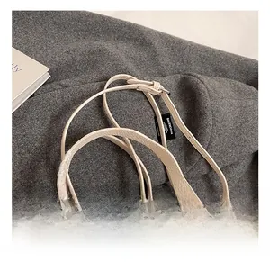 Detail showing cream lychee grain leather, dual handles, and delicate lace bow accent