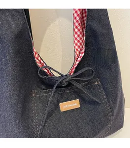 Close-up of denim tote bag featuring a bow detail and red gingham lining