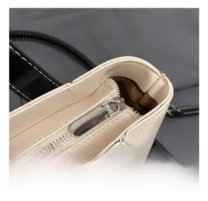 Macro detail of the smooth silver zipper and stitching on a two-tone minimalist handbag